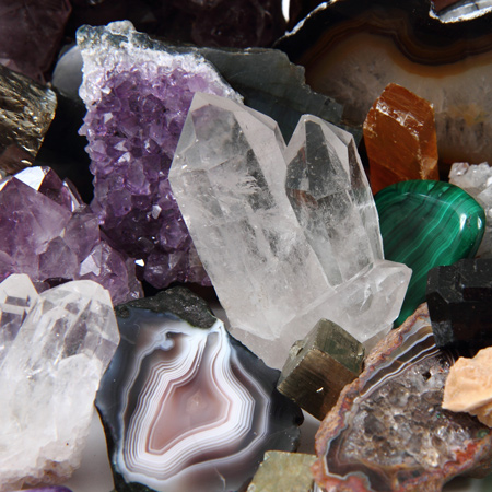 Clear quartz cyrstals, amethyst, jade, onyx, amber, and other gemstones in a pile.